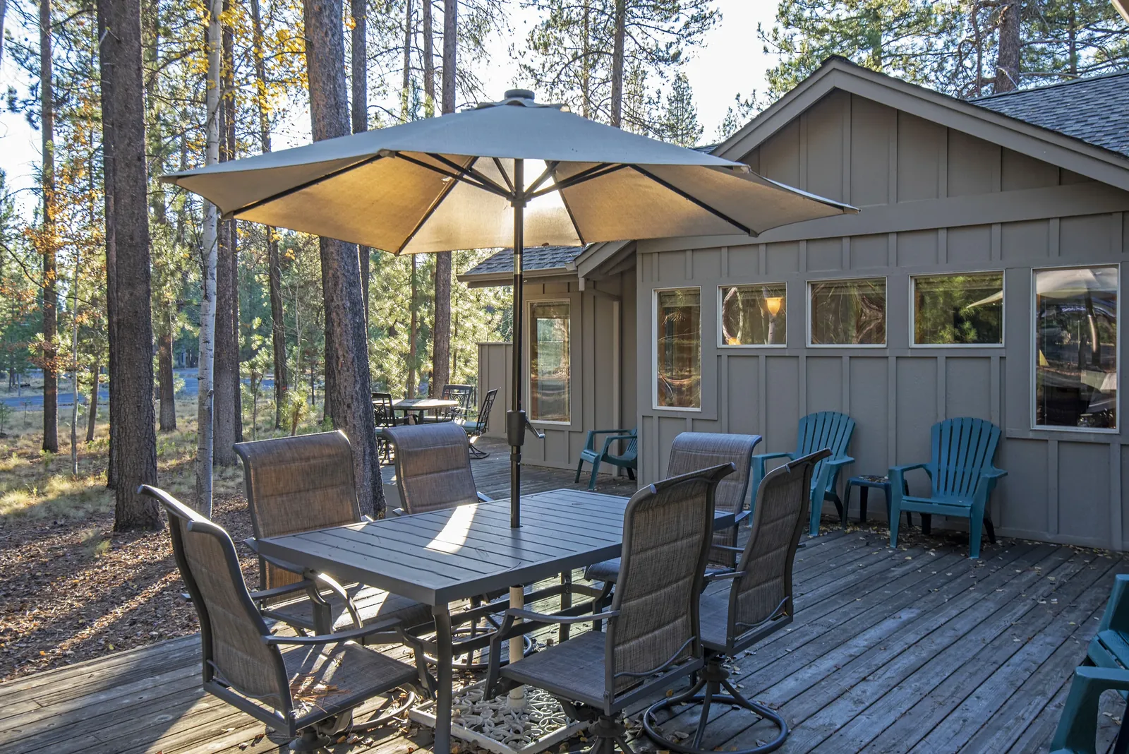 Deck with umbrella table seating six and Adirondack chairs